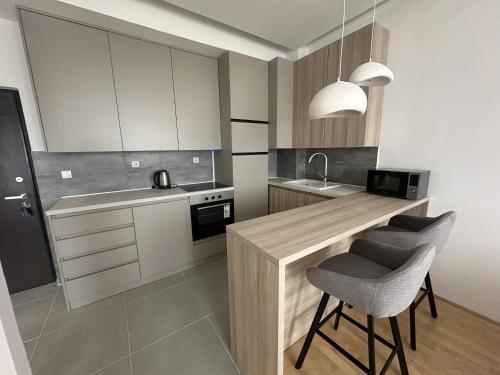 a kitchen with a counter with two chairs and a sink at City Center Apartment in Zrenjanin