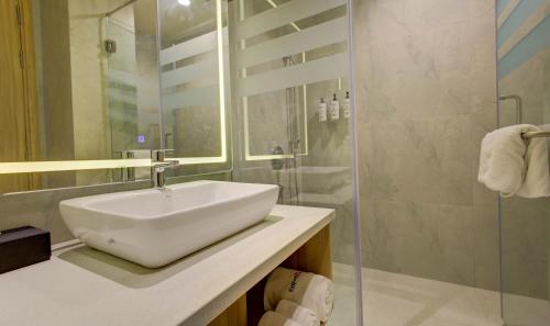 a white bathroom with a sink and a shower at Cygnett Inn in Dibrugarh
