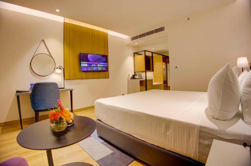 a hotel room with a large bed and a table at Cygnett Inn in Dibrugarh