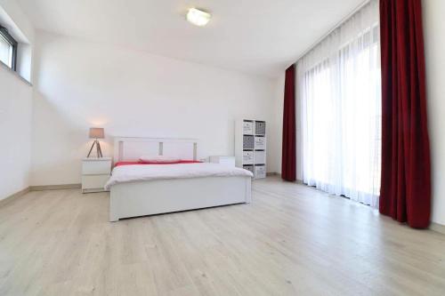a white bedroom with a bed and red curtains at Luxusný rodinný dom v Trenčíne in Trenčín
