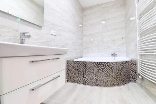 a white bathroom with a sink and a tub at Luxusný rodinný dom v Trenčíne in Trenčín