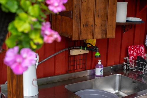 a kitchen sink with a faucet and pink flowers at Härbre Cabin in Årjäng
