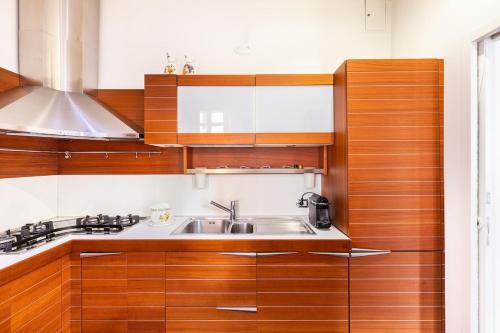 una cucina con mobili in legno e un lavello di La corte di Merlino - Apt centrale di pregio a Roma