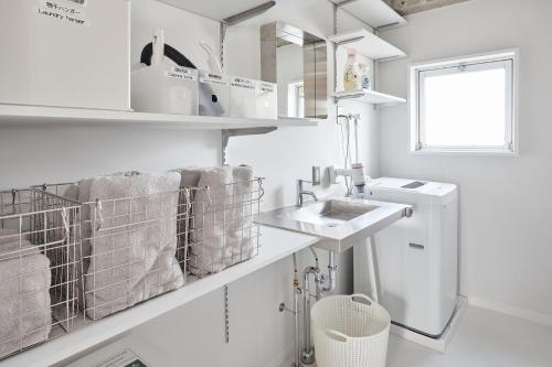 a white bathroom with a sink and towels at Koubanoyado in Tokyo