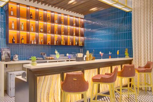 a restaurant with a bar with yellow chairs and bottles at Cygnett Inn in Dibrugarh