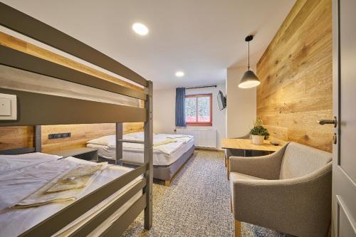 a hotel room with two beds and a chair at Hotel Bouda Jana in Pec pod Sněžkou