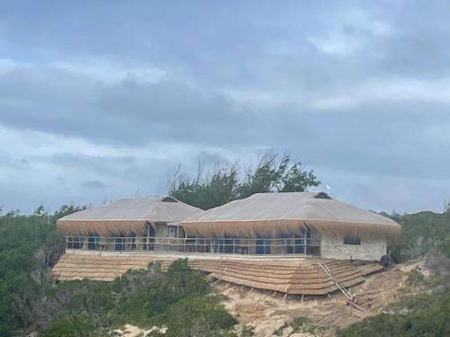 a large building with a roof on top of a hill at Izmaan Lodge Pomene in Fombeni
