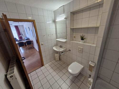 a white bathroom with a toilet and a sink at Fewo-31-Holly in Orth