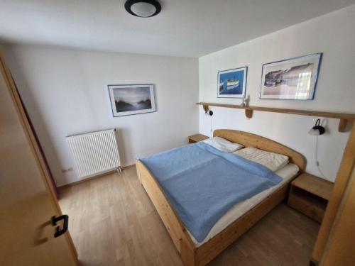 a bedroom with a bed with a blue blanket at Fewo-32-Hauke in Orth