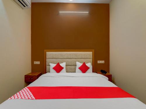 a bedroom with a white bed with red pillows at Hotel O B.S Celebration in Lucknow