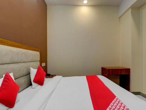a bedroom with a white bed with red pillows at Hotel O B.S Celebration in Lucknow