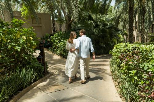 a man and a woman walking down a sidewalk at Jumeirah Al Qasr Dubai in Dubai