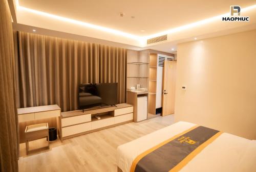 a hotel room with a bed and a flat screen tv at Hào Phúc Hotel 