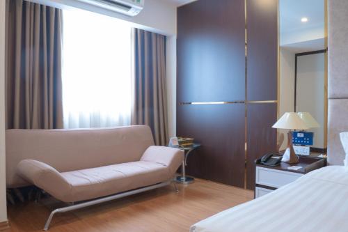 a hotel room with a couch and a bed at Bao Son International Hotel in Hanoi