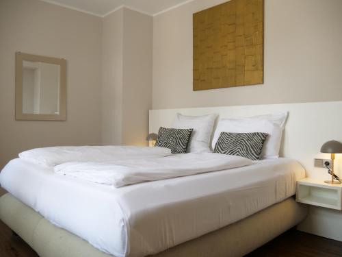 a white bedroom with a large white bed with pillows at Living am Carlsplatz Apartment in Düsseldorf