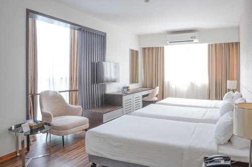 a hotel room with two beds and a chair at Bao Son International Hotel in Hanoi