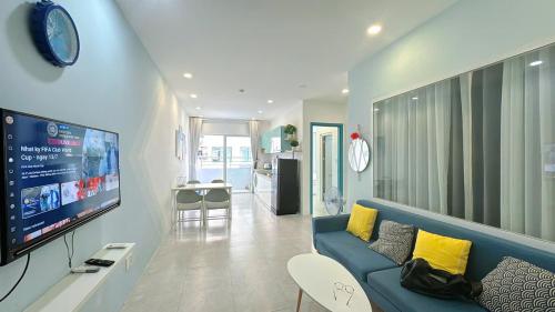 un soggiorno con un divano blu e una TV di Ubuntu Mường Thanh Nha Trang Apartment a Nha Trang