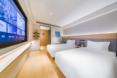 a hotel room with a large bed and a flat screen tv at JI Hotel Beijing Zhongguancun Suzhou Street in Beijing