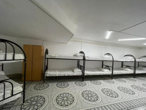 a room with three bunk beds and a floor at Adeke Hostel in Atyraū