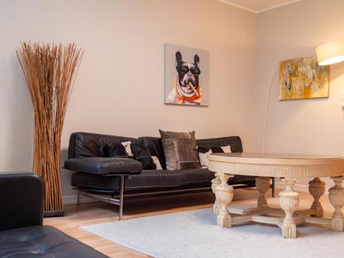 a living room with a black leather couch and a table at Living am Carlsplatz Apartment in Düsseldorf