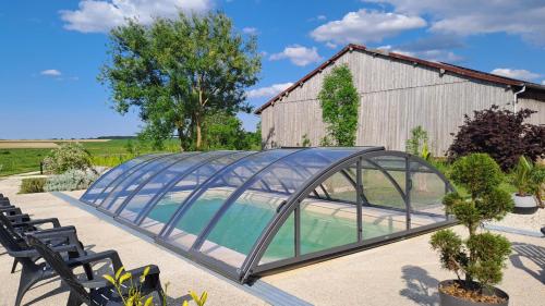 a glass greenhouse in front of a building at Gîte des bulles in Bailly-le-Franc