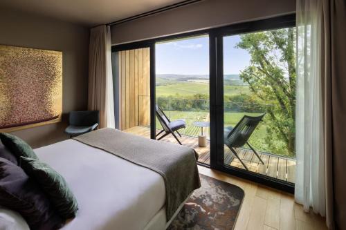a bedroom with a bed and a large window at LOISIUM Wine & Spa Hotel Champagne in Mutigny
