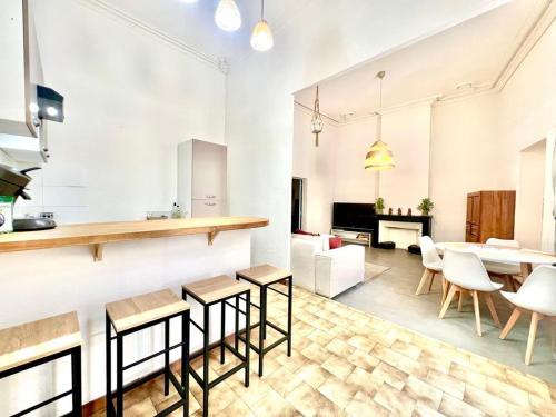 a kitchen with white walls and wooden tables and chairs at Le Logis du Château , Charme au cœur de Sommières in Sommières