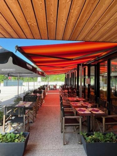 a row of tables and chairs under a red umbrella at Hôtel Restaurant AKENA Molinges - La Brocatelle in Saint-Claude
