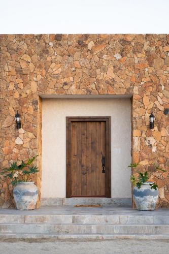 a wooden door in a stone building with two pots at Baja Toscana in Valle de Guadalupe