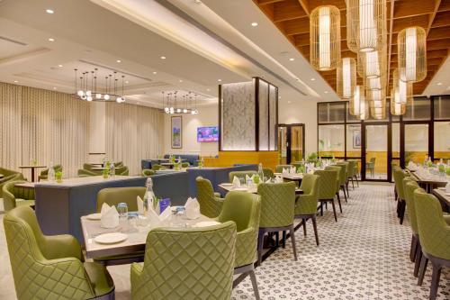 a dining room with tables and green chairs at Cygnett Inn in Dibrugarh