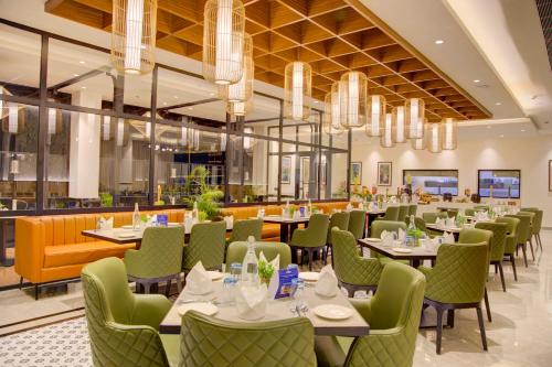 a dining room with tables and green chairs at Cygnett Inn in Dibrugarh
