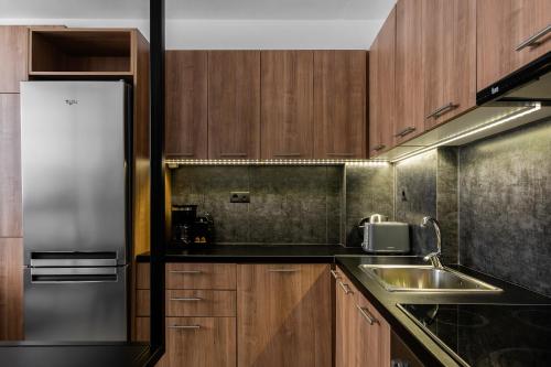 a kitchen with wooden cabinets and a stainless steel refrigerator at The Gate by Zoia Living in Athens