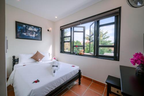 a bedroom with a bed and a window at Du Yen Hoi An Villa in Hoi An
