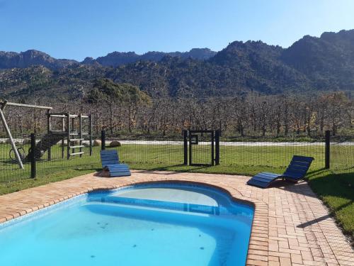 una piscina con due sedie e un parco giochi di Rhodene Farm Cottages a Prince Alfreds Hamlet