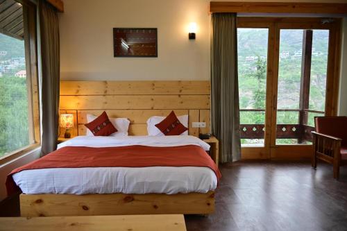 - une chambre avec un grand lit dans une pièce dotée de fenêtres dans l'établissement Rigzin House by Meghsparsh Resorts, à Palchān