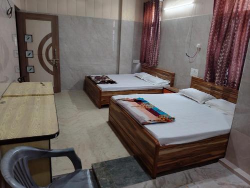 a room with two beds and a table and a chair at Kalindi Blessings Deluxe Guest House in Mathura