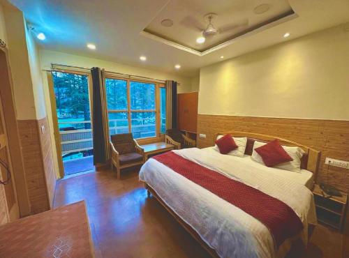 a bedroom with a large bed and a window at Hotel Krishna Place River Side #Gym #Playing Zone #Roftop Cafe #Balcony #Parking in Kasol
