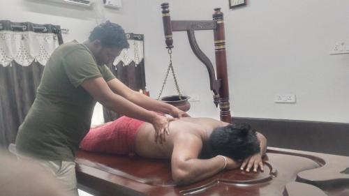 a man getting a massage from a man laying on a bed at Siesta Inn - RP Resort in Chennai