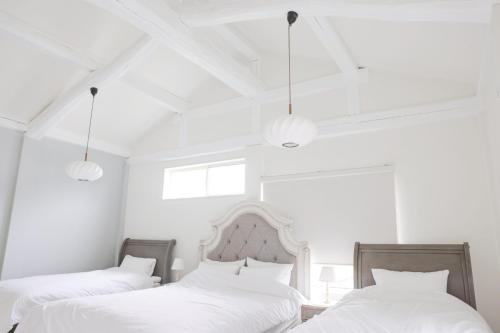 two beds in a bedroom with white walls and lights at 静岡 伊豆高原 ペットと泊まれるプライベートヴィラ Tous les doudouトゥレ ドゥドゥ in Ito