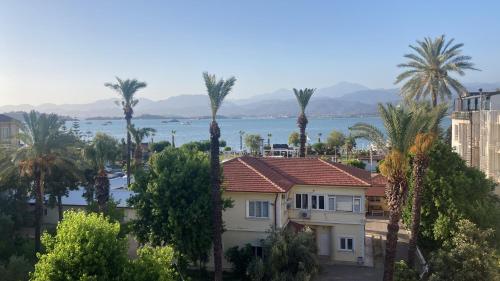 a view of a house and palm trees and the water at Modern Flat Walk to Shops, Cafes Harbour in Fethiye