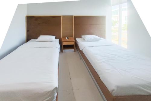 two twin beds in a room with a table at Urbanview Hotel Syariah UIN Mataram in Mataram
