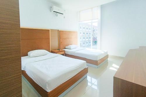 a bedroom with two beds and a window at Urbanview Hotel Syariah UIN Mataram in Mataram