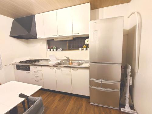 a kitchen with white cabinets and a stainless steel refrigerator at 犬山城に近い大人数宿泊が可能で駐車場あり in Inuyama
