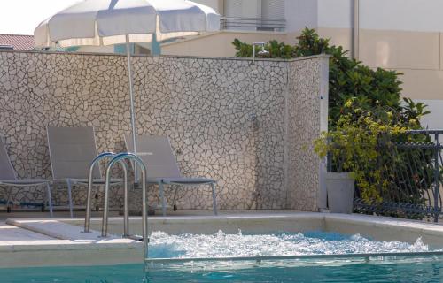 a pool of water with chairs and an umbrella at Hotel Jesulum in Lido di Jesolo