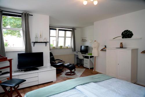 a bedroom with a bed and a desk with a television at Eifel Fewo in Neuerburg