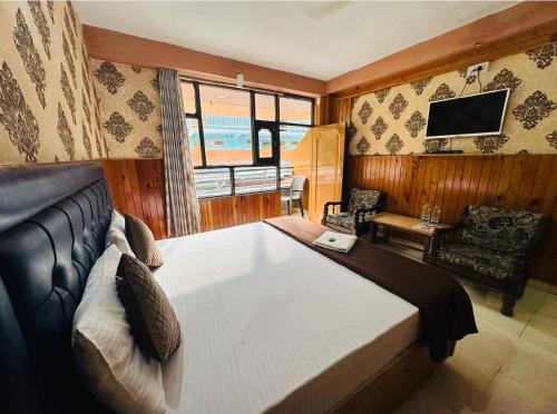 a bedroom with a large bed and a television at Hotel Krishna Place River Side #Gym #Playing Zone #Roftop Cafe #Balcony #Parking in Kasol