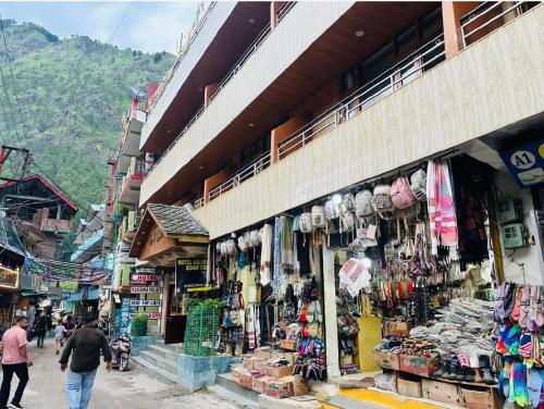 a market with people walking in front of a store at Hotel Krishna Place River Side #Gym #Playing Zone #Roftop Cafe #Balcony #Parking in Kasol