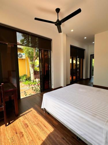 Un dormitorio con una cama blanca y un ventilador de techo. en Richico Hoi An Villas, en Thanh Ðông (1)