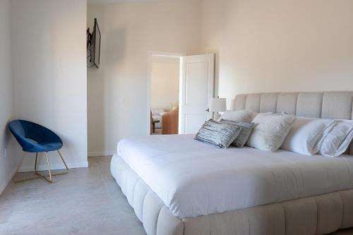a bedroom with a large white bed with a blue chair at Villas Baja Toscana de Rancho Olivares in Ensenada