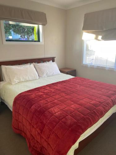 a bedroom with a large bed with a red blanket at Cosy Cottage in Wellington